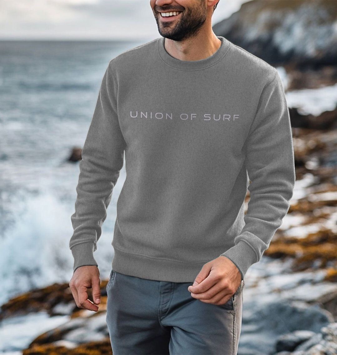 Model wearing Relaxed Fit Coastal Sweatshirt by the ocean, showcasing casual coastal style
