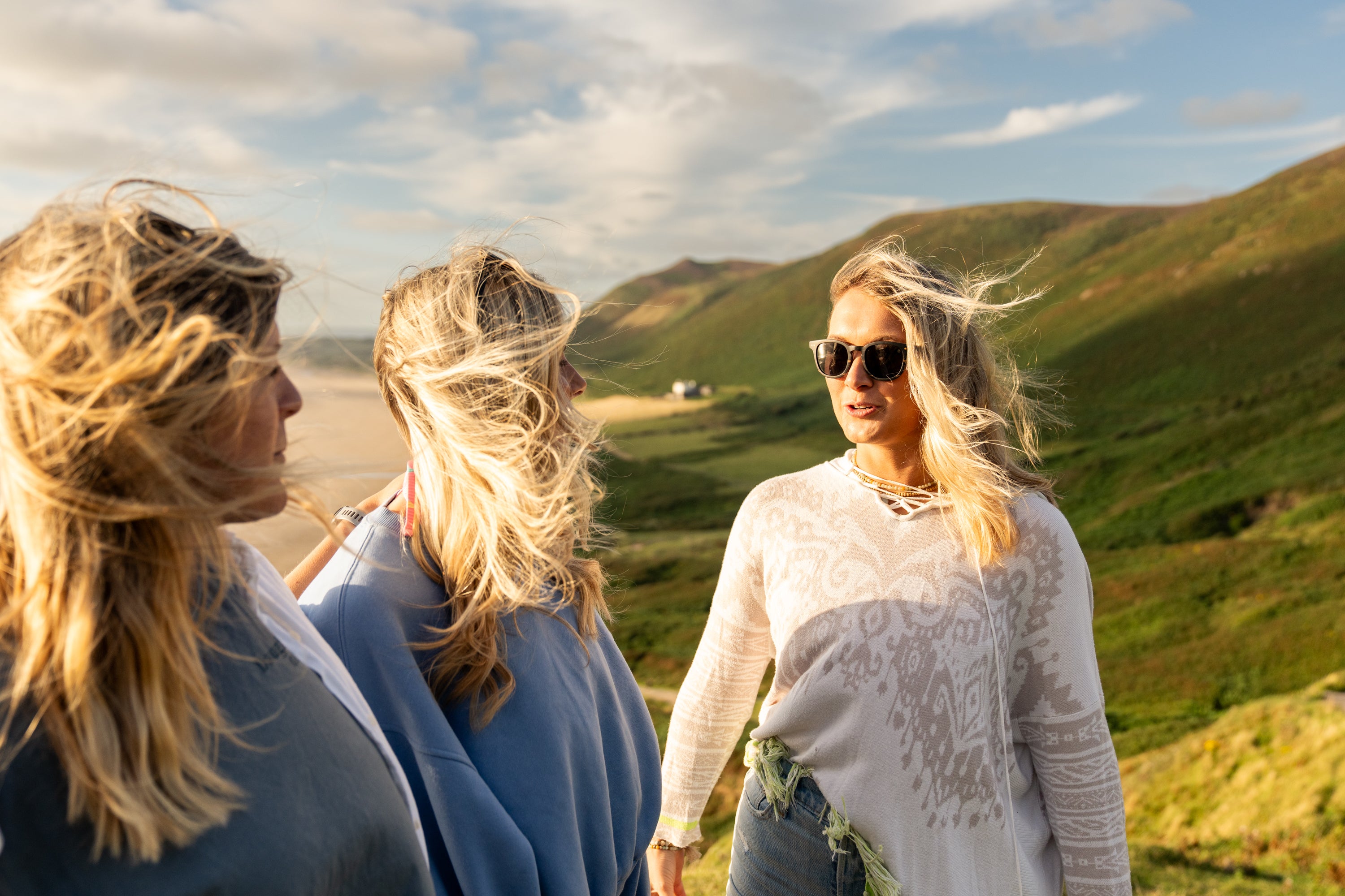 Models standing on cliff top wearing wood framed sunglassez