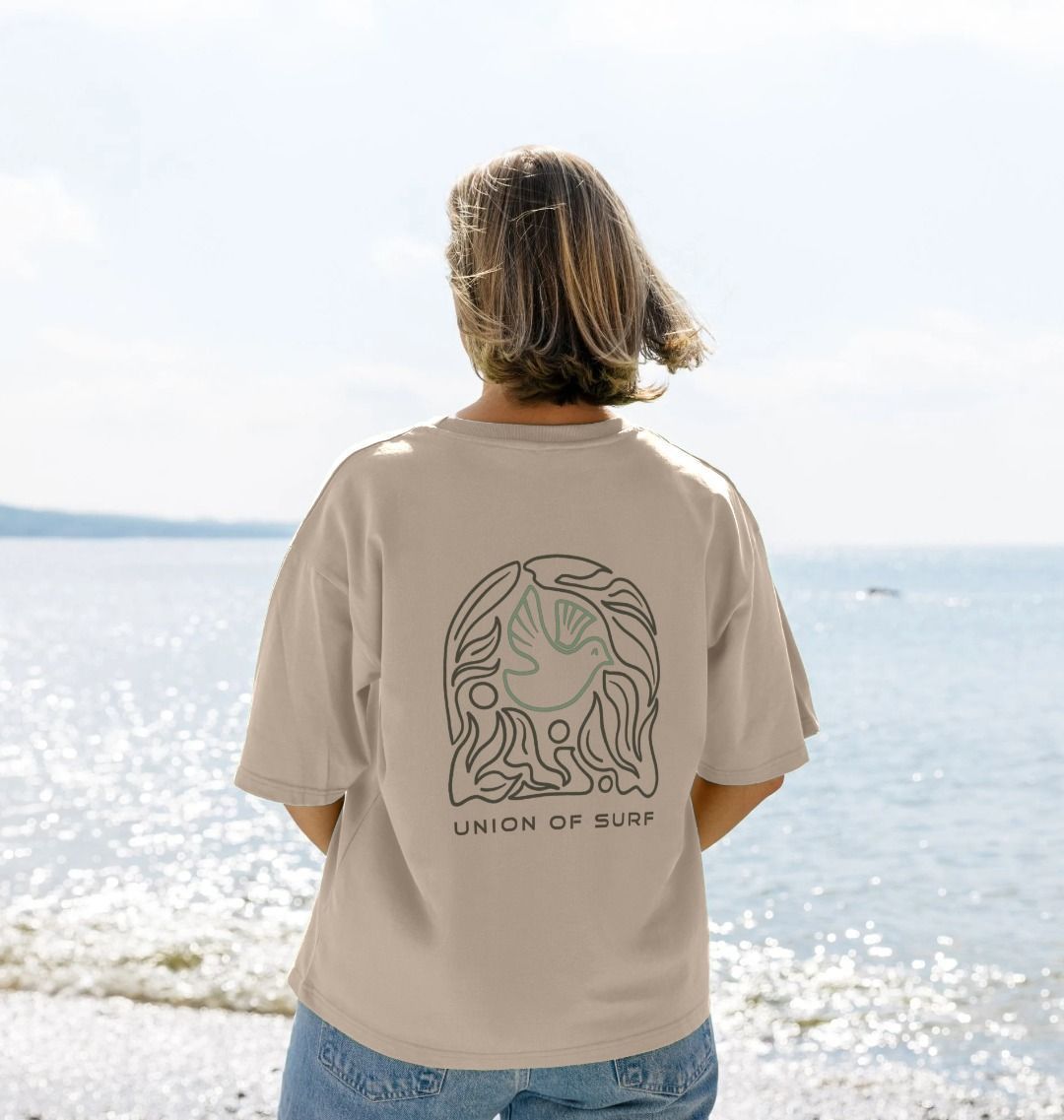 Person wearing a beige t-shirt with 'Union of Surf' design at the beach