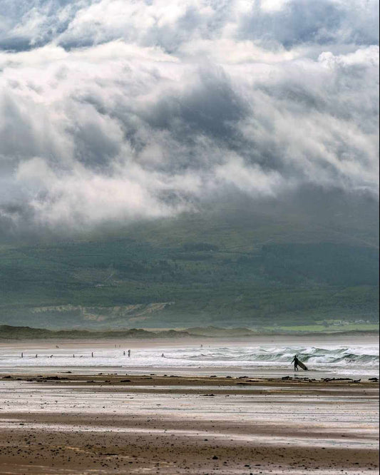 Surfers riding waves at popular UK surf break with coastal scenery