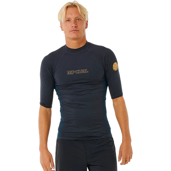 Rip Curl Mens Dawn Patrol short-sleeve rash vest in dark charcoal, with a snug fit, gold chest logo and sleeve emblem.