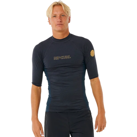 Rip Curl Mens Dawn Patrol short-sleeve rash vest in dark charcoal, with a snug fit, gold chest logo and sleeve emblem.