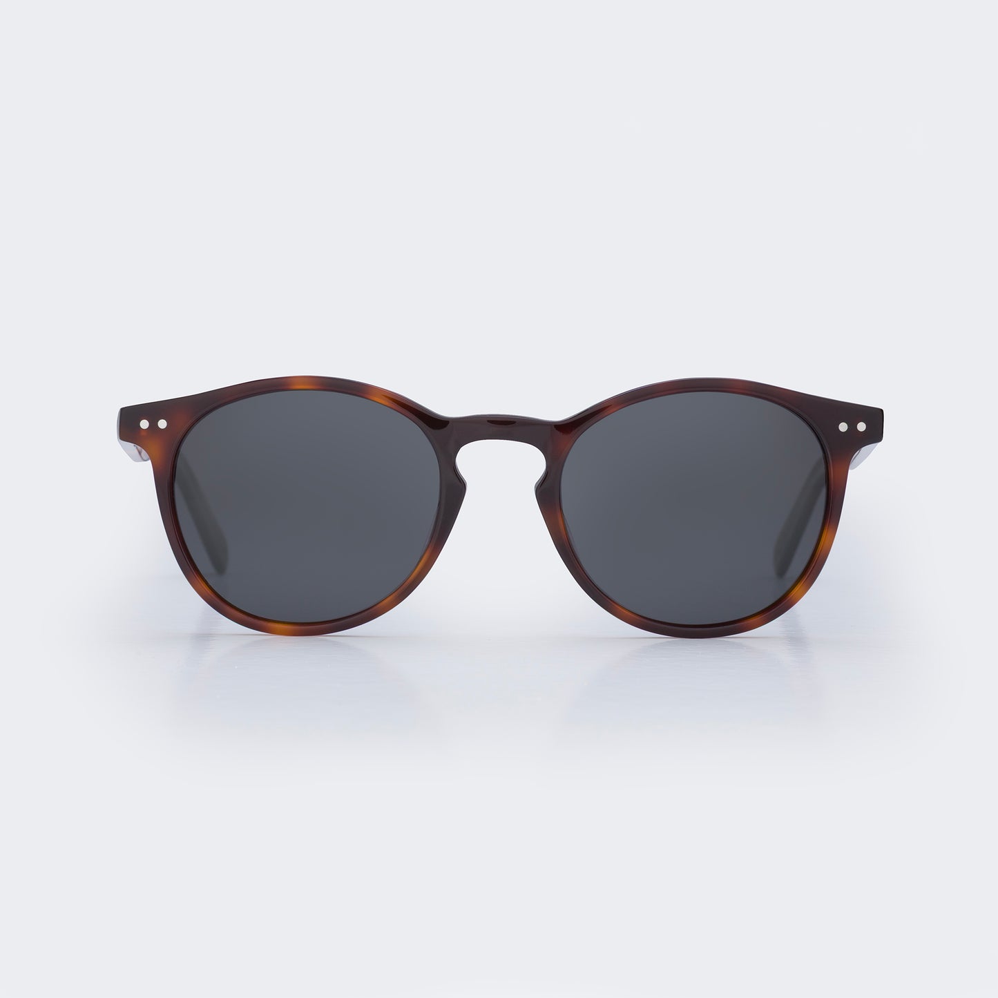 Sunglasses with tortoiseshell frame and dark lenses on a light gray background