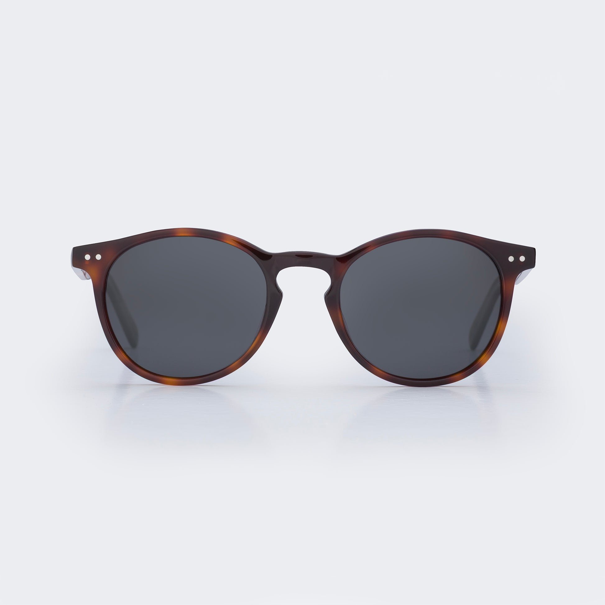 Sunglasses with tortoiseshell frame and dark lenses on a light gray background