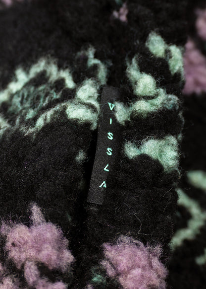 Vissla Hiking Ice sherpa fleece fabric, black with mint and lilac abstract pattern and a woven brand label.