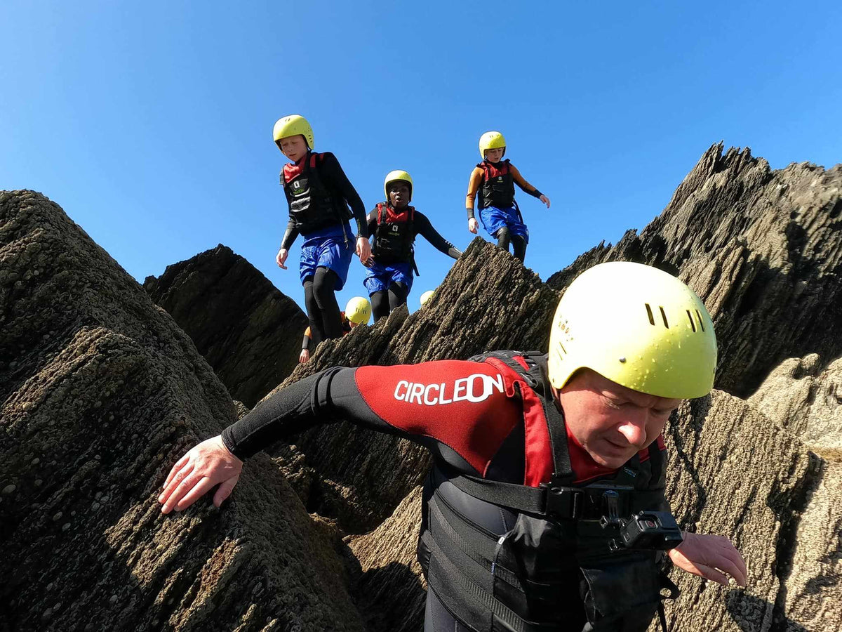 ARC 5/4mm ADULT wetsuit in black and red neoprene, with yellow helmet, back zip and protective panels for coasteering.
