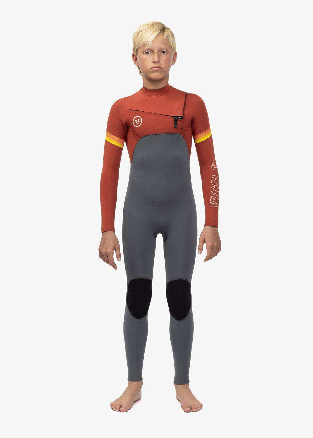 Vissla 7 Seas Boys wetsuit in rust red and gray neoprene with black knee pads, chest zip, and yellow arm stripes.