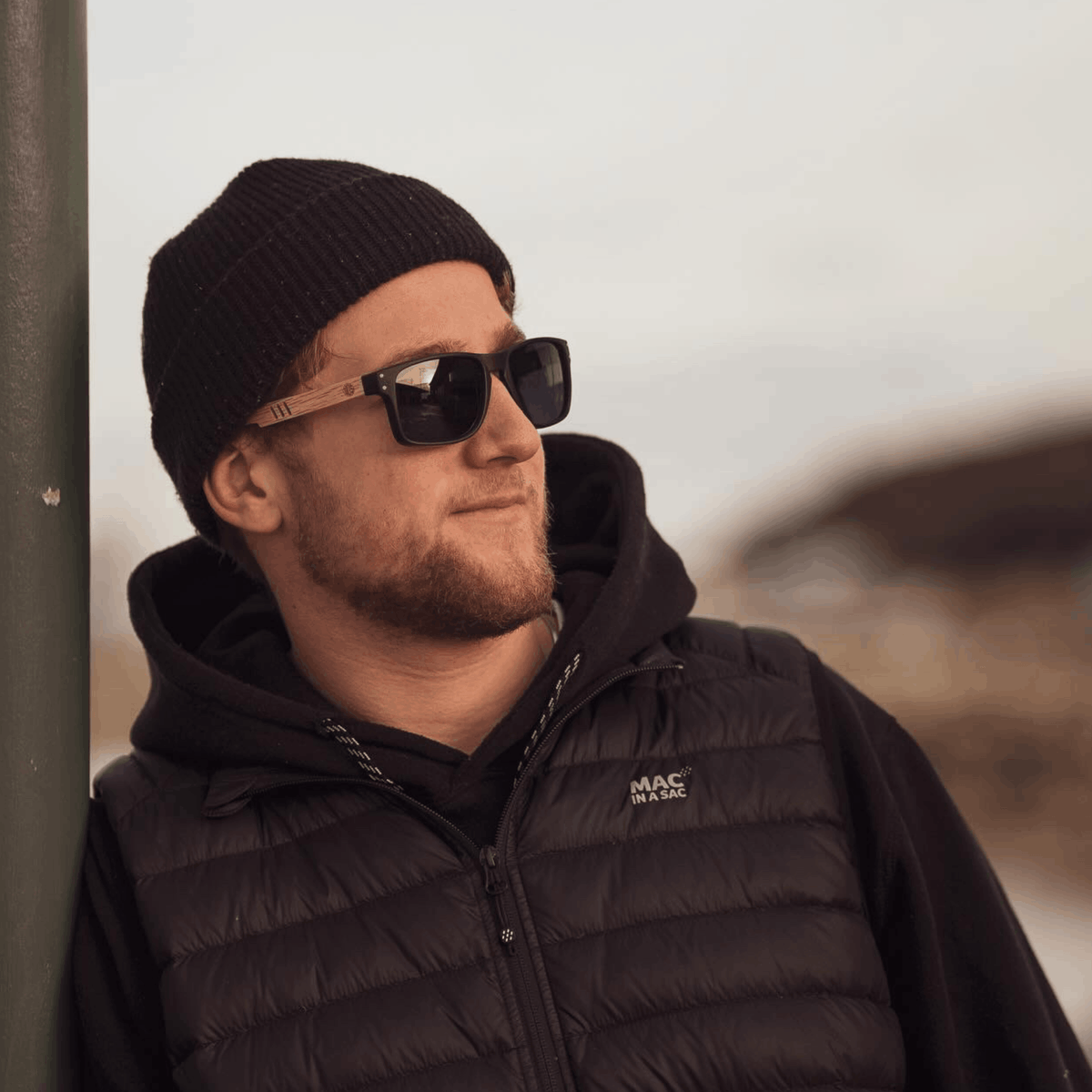 Man wearing Bells Beach polarised sunglasses and a black beanie outdoors.