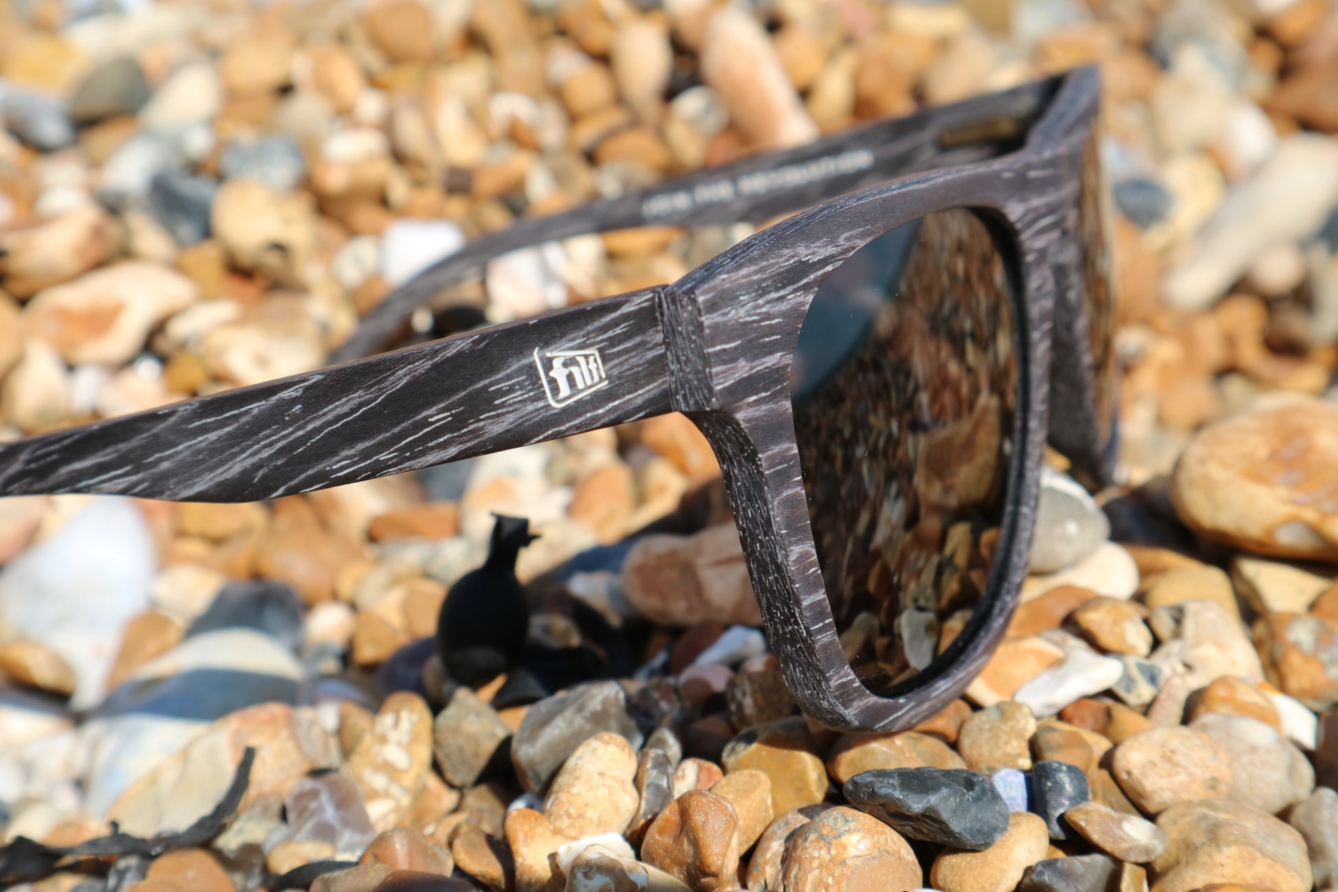 Unisex wooden sunglasses with polarised lenses. Sunglasses photographed on a beach. best for Eye protection against glare.