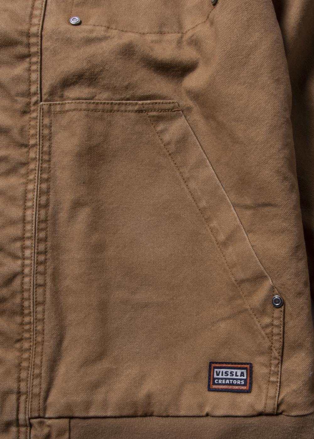 Vissla Creators Grit Jacket in brown cotton canvas, featuring a large angled pocket, metal snaps, and logo patch.