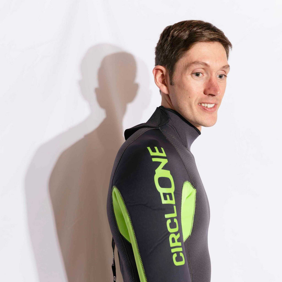 Mens 4/3mm Spring Wetsuit in black neoprene with bright lime green panels and bold sleeve lettering, featuring a high neck and back zip.