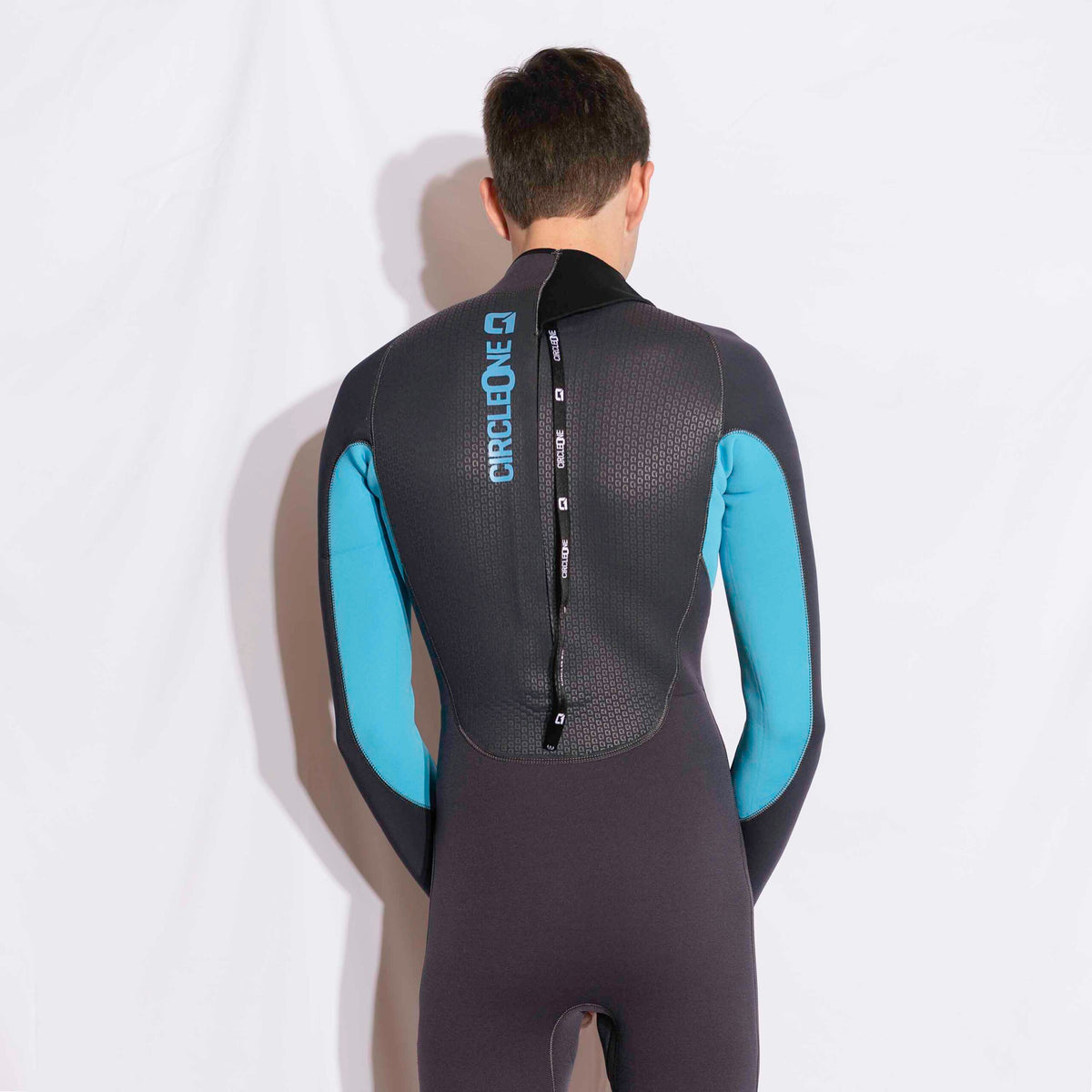 Mens 5/4mm Winter Wetsuit in black neoprene with bright blue arm panels, textured back and vertical zip closure.