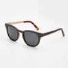 Shaka Black-Daughters of the Sea sustainable black sandalwood sunglasses with polarized lenses on beach background