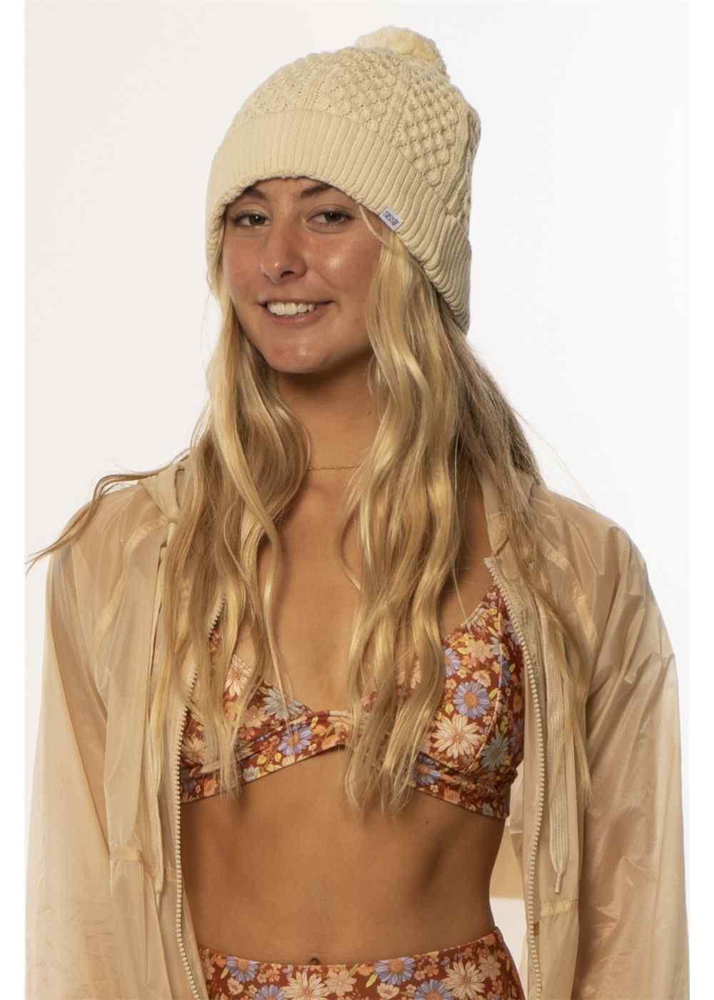 Sisstrevolution Fantasy Beanie in cream knit with a chunky cable pattern, ribbed cuff, and soft pom-pom top.